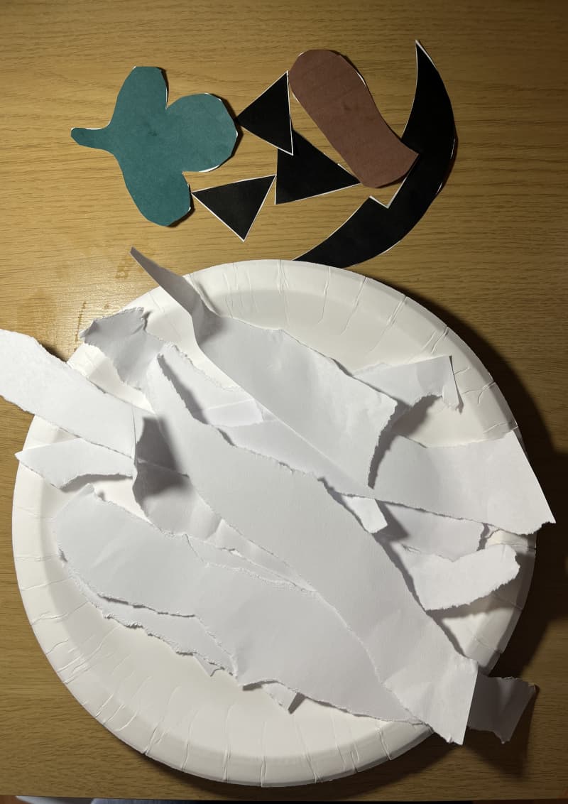 Κολοκύθα Halloween φτιαγμένη από χάρτινο πιάτο βαμμένο πορτοκαλί με χαρακτηριστικά από λωρίδες χαρτιού