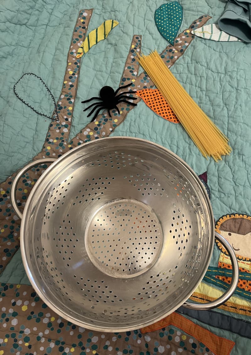 Colander with spaghetti forming a spider's web — Halloween play for children
