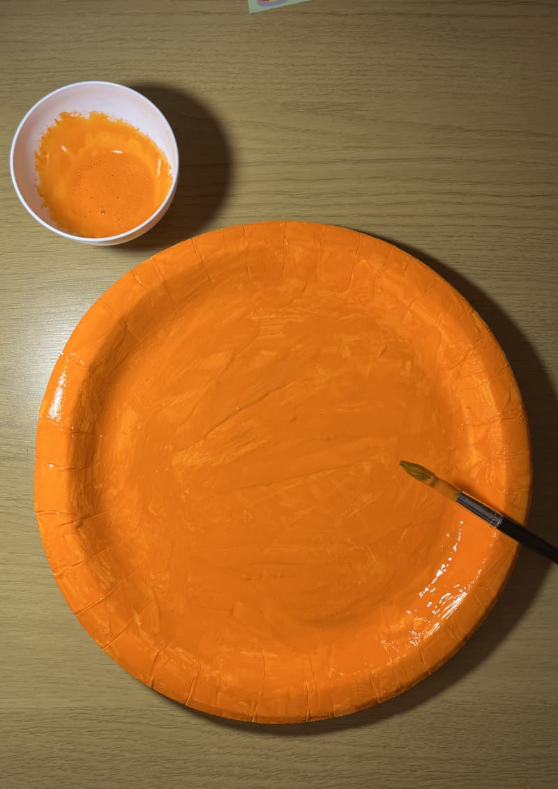 Κολοκύθα Halloween φτιαγμένη από χάρτινο πιάτο βαμμένο πορτοκαλί με χαρακτηριστικά από λωρίδες χαρτιού