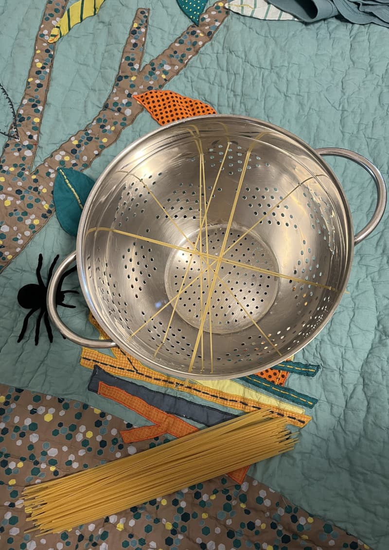 Colander with spaghetti forming a spider's web — Halloween play for children