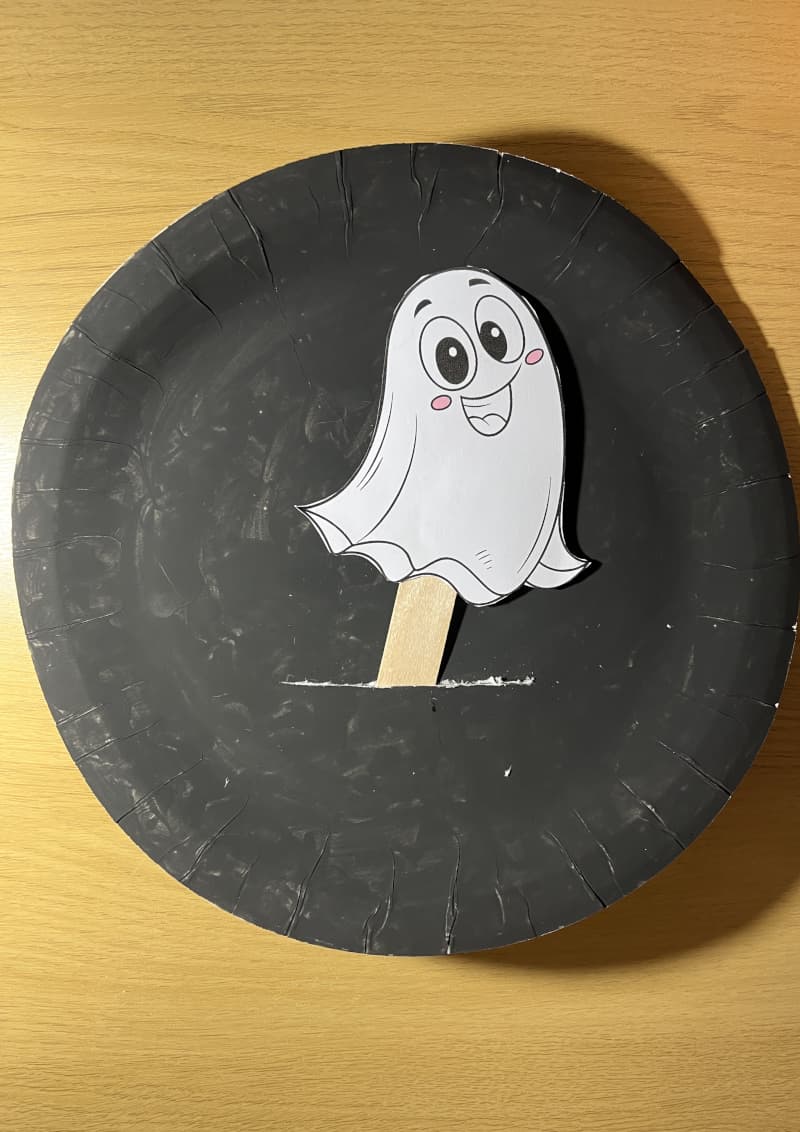 Φαντασματούλης χειροτεχνία φτιαγμένη από λευκό χάρτινο πιάτο και ξυλάκι — Halloween χειροτεχνία