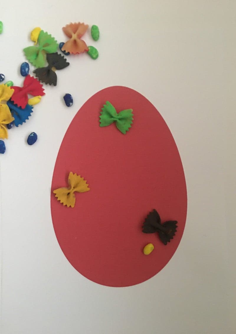 Craft for kids for Easter. Easter egg with colored pasta and beans.